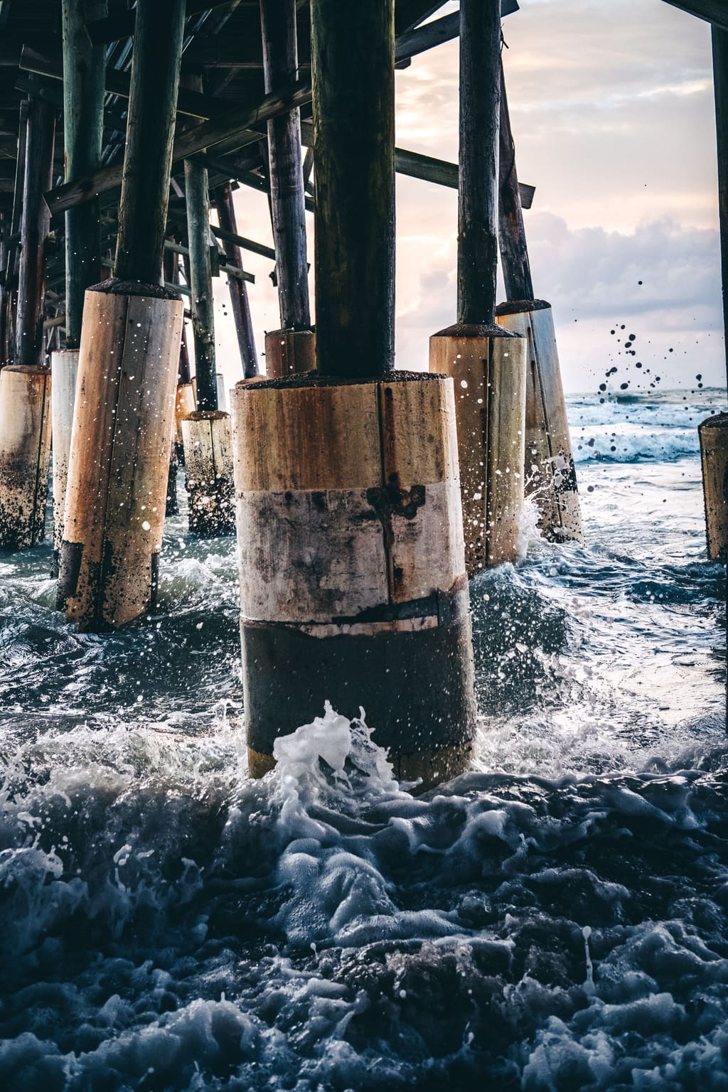 Waves crashing against wooden pier posts