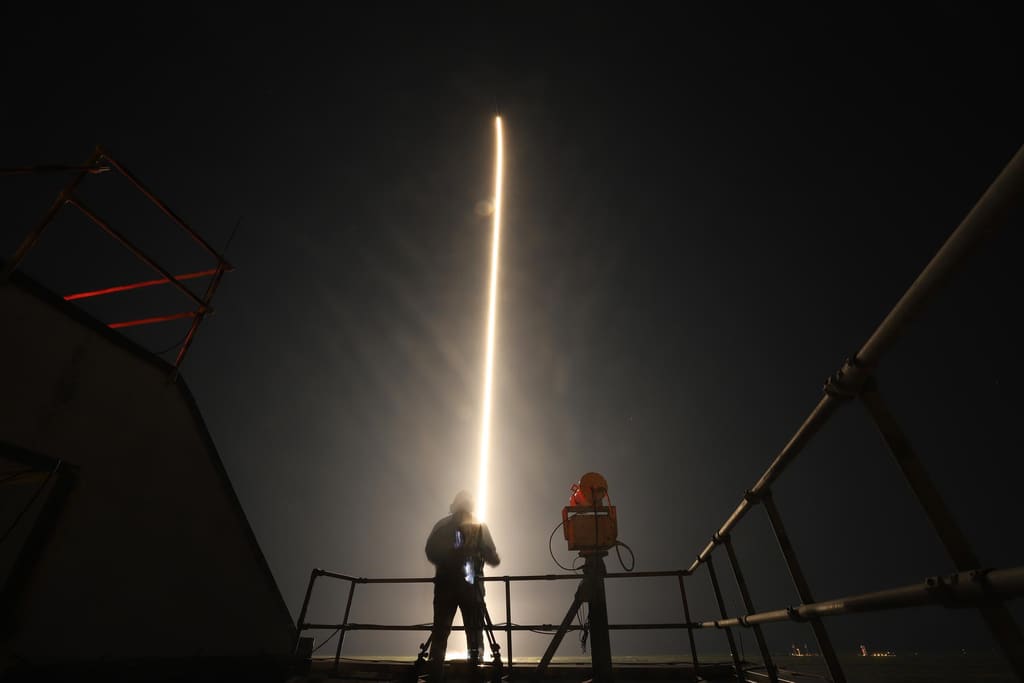Gente viendo un cohete cruzar el cielo nocturno